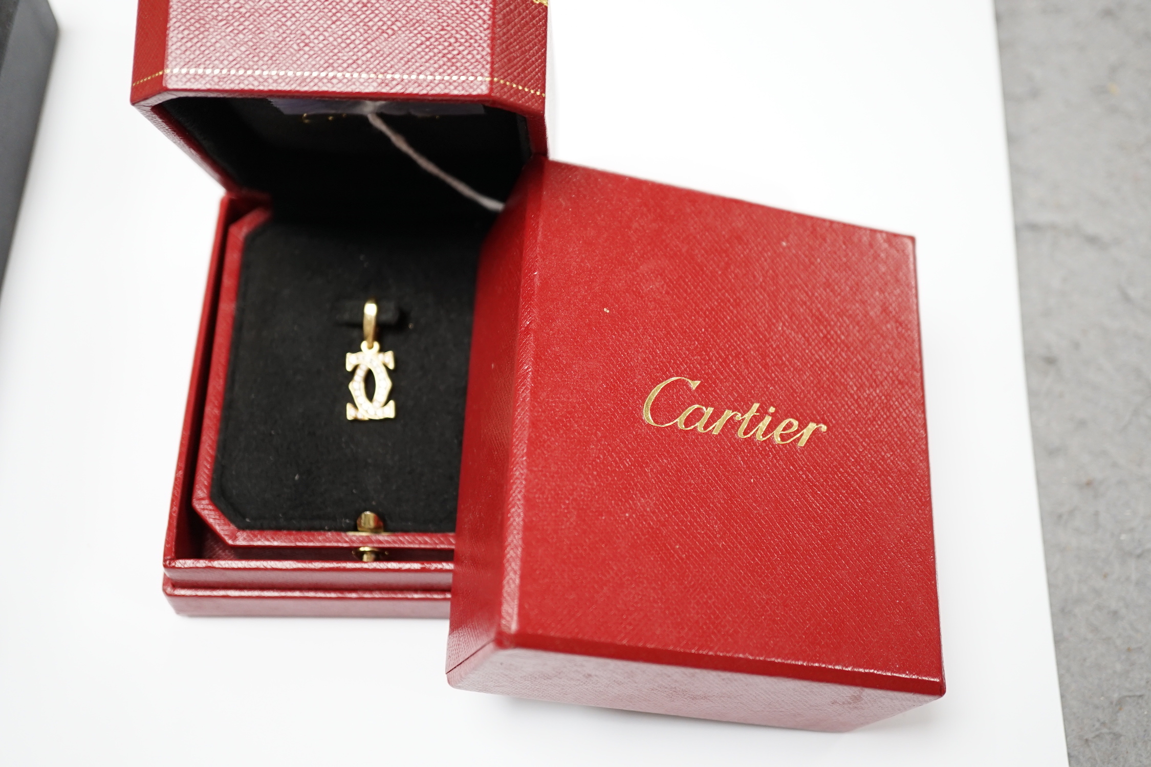 A modern Cartier 750 yellow metal and diamond chip set double C drop pendant, signed and numbered NE6304, overall 25mm, gross weight 2.6 grams, with Cartier box.